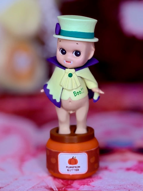 Halloween vampire figurine on orange base, mint hat and purple cape, light green suit
