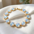 Gold-tone crystal bracelet with opal blue round cushion stones and hinge clasp.