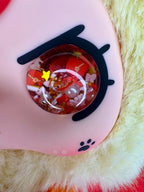 Close-up of plush doll’s glittery red eye with dark lashes and star charm details