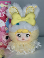 Plush bunny charm doll close-up with yellow bow ears, blue eyes, lace cream outfit
