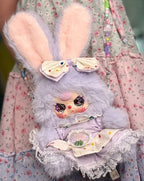 Rabbit plush coin purse with lavender ruffled outfit, coin-purse face patch, and keychain strap.