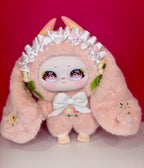 Pink plush blind box figure with hood, white ruffled trim, and heart-eyed face