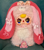 Plush rabbit toy with pink ears and hood, glittery eyes, and small belly badge