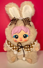 Cream plush bunny with big plaid bow, pink hair, and round blue eyes