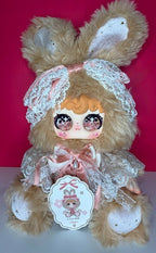 Collectible bunny plush in pastel lace dress with dangling charm and pink bow headband.