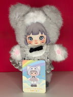 Gray plush articulated doll in bear-ear hood, wearing white dress; includes “Curly-Tail Kitty” tag