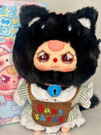 Plush black baby kitten with white muzzle, lace-trim dress, and blue pendant on chest