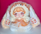 Kawaii plush doll with white hood, orange dress, ruffled skirt, and character prints on sleeves