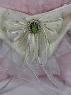 Close-up of jeweled pale gold bow with dangling bead strings on plush collar