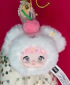 White plush pendant toy with pink face, green charm, and big round eyes