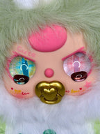 Light green plush bunny face close-up with glittery eyes, pink nose, gold heart
