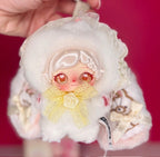 White fluffy hooded plush doll with lace details, yellow bow, and warm amber eyes.