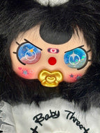 Close-up of black plush bunny face with blue star eyes, red nose, and gold heart charm