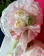 Pink lace and ribbon bow with rose detail on green plush
