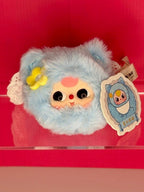 Powder blue plush hair scrunchie with cute face, yellow flower, and tag