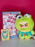 Green fluffy plush pendant with big orange eyes and blue dress with teardrop details