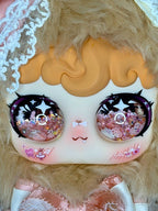 Collectible bunny plush face close-up with glitter eyes and pink heart accents.