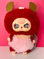 Collectible fuzzy plush character with red fur, starry eyes, and yellow scarf
