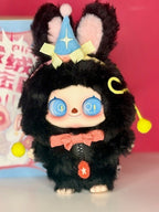 Black fluffy plush pendant with blue star headpiece, smiling face and yellow pom details.