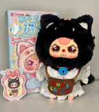Black plush kitten doll with white lace-trim bib, “Baby three” apron detail