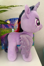 Purple plush pony with horn and glittery wing details, side profile