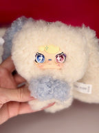 Plush bunny bag charm with off-white fur, blue and pink glitter eyes, and light cloud belly