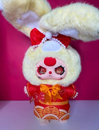 Front view plush doll with fluffy light yellow hood, red bow, and red-and-gold outfit