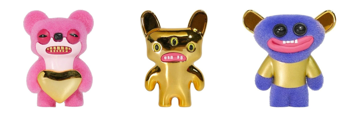 Three monster figures: pink plush, gold cat, and blue plush in gold shirt