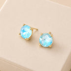 Sterling silver post round glass stud earrings with light blue gemstone-style center