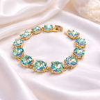 Gold-tone crystal bracelet with light aqua round cushion stones and hinge clasp.