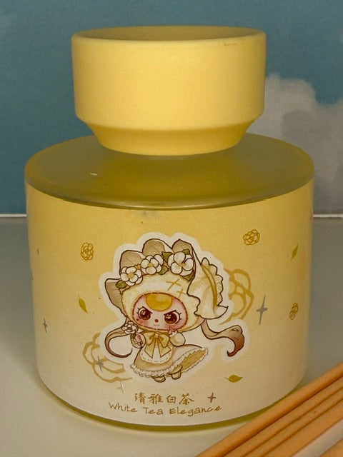 Yellow ceramic reed oil diffuser jar with character illustration and “White Tea Elegance” text