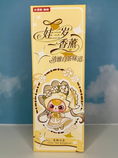 Yellow scented reed oil diffuser box with character illustration and “White Tea Elegance”