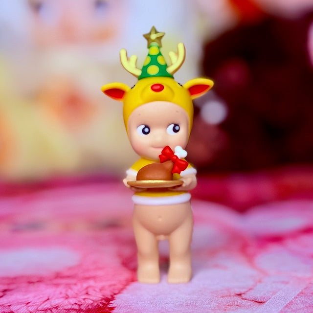 Sonny Angel yellow reindeer figure holding a meal tray, green tree hat, red bow