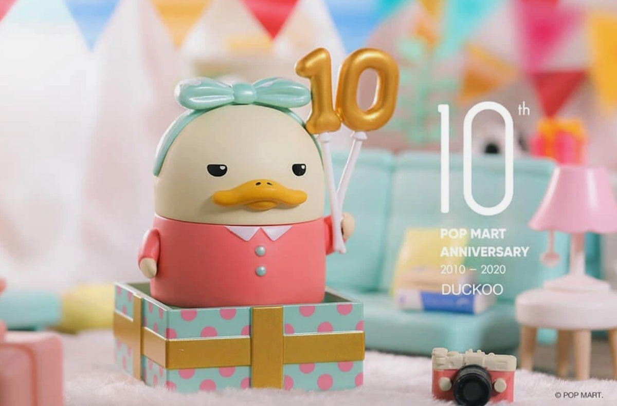 Duckoo collectible figure in red vest holding a gold “10” anniversary balloon