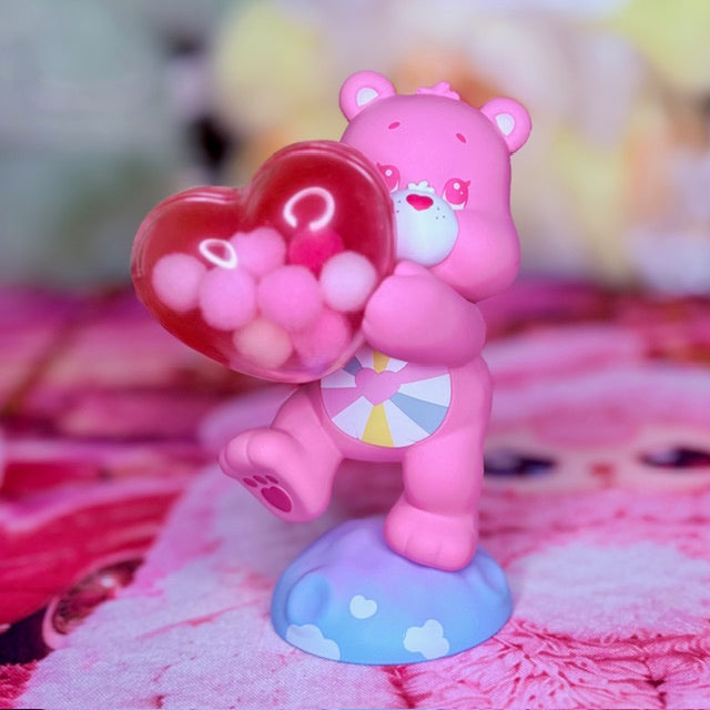 Pink Care Bears figure holding a heart-shaped accessory, standing on a blue cloud base