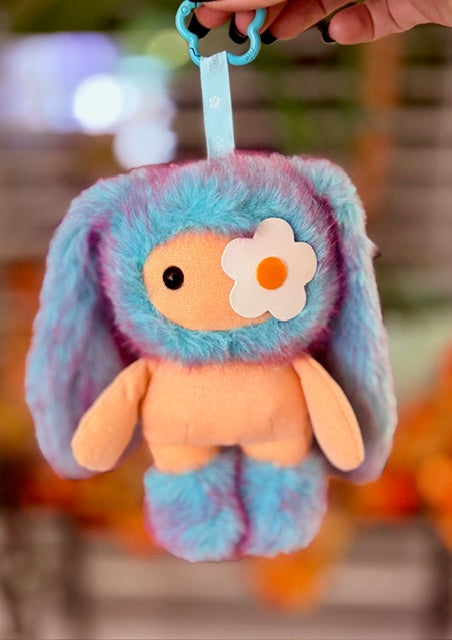 Blue plush bunny bag charm with orange belly and white flower patch, held by hook