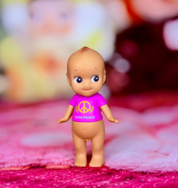 Full-body front view pink mini figurine with peace symbol shirt and blue eyes
