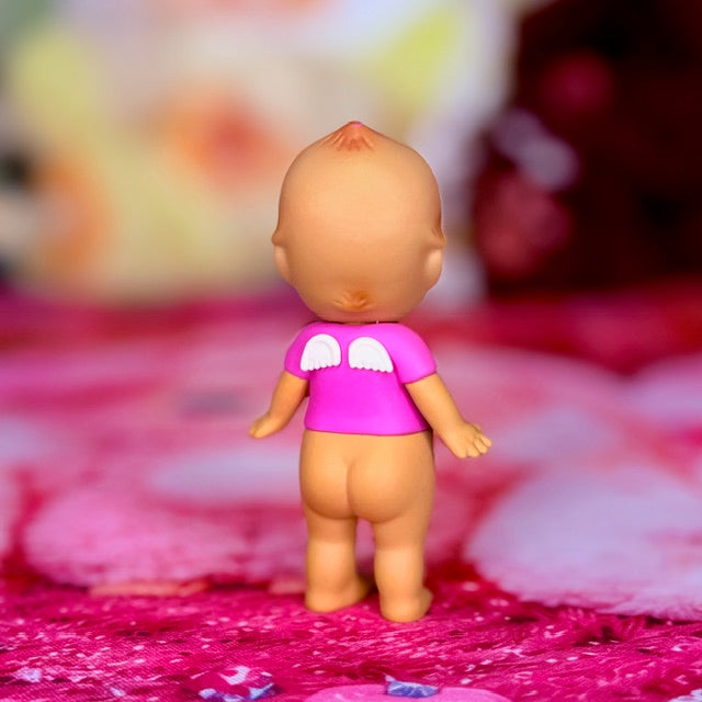 Rear view pink mini figurine with purple shirt, standing on pink fabric