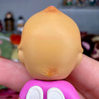 Close-up of pink mini figurine head and purple shirt collar