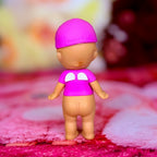 Pink mini figurine with purple shirt and white peace symbol on chest, standing on fabric
