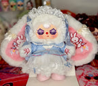 Plush baby figure in blue dress with white lace bonnet, ruffled skirt, pink boots