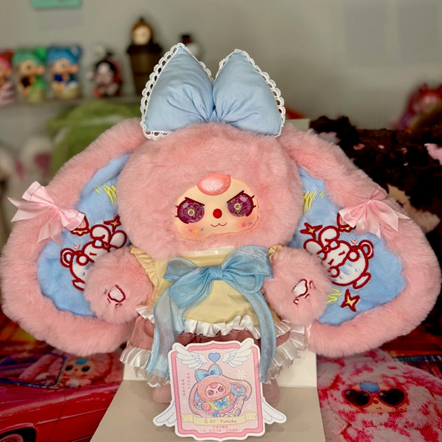Pink and light blue plush figure holding gift tag on display box, sailor dress and bow