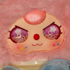 Pink plush figure face with purple glitter eyes, flower details, and smile