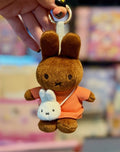Plush brown bunny keychain with light blue character, wearing orange outfit and gold clasp.