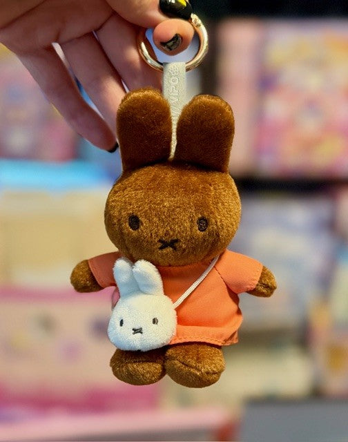 Plush brown bunny keychain with light blue character, wearing orange outfit and gold clasp.
