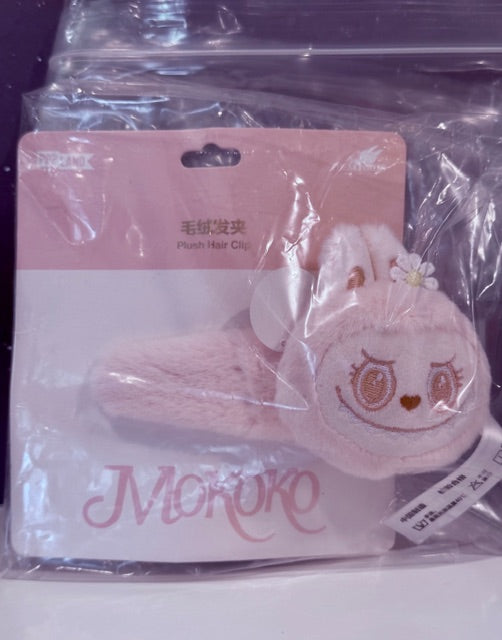 Pastel pink plush hair clip with cute face and small flower detail