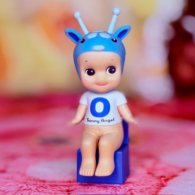 Upright blue vinyl figurine with antennae, big letter O on shirt, and dark eyes