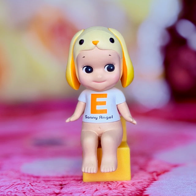Lop-eared rabbit figurine with blue shirt, orange print, standing on yellow base