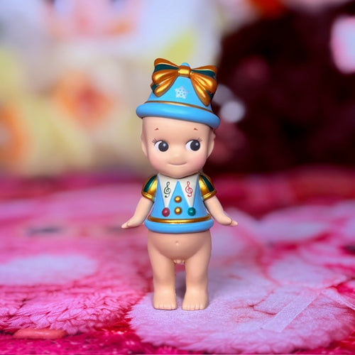 Sonny Angel Christmas bell figurine, front view with blue bow hat and gold trim