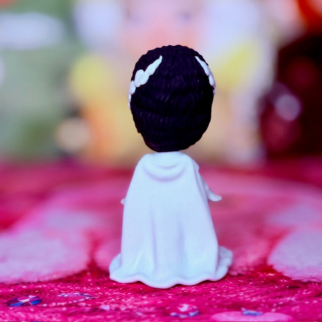Custom vinyl doll back view wearing white gown with dark purple head and white headband.